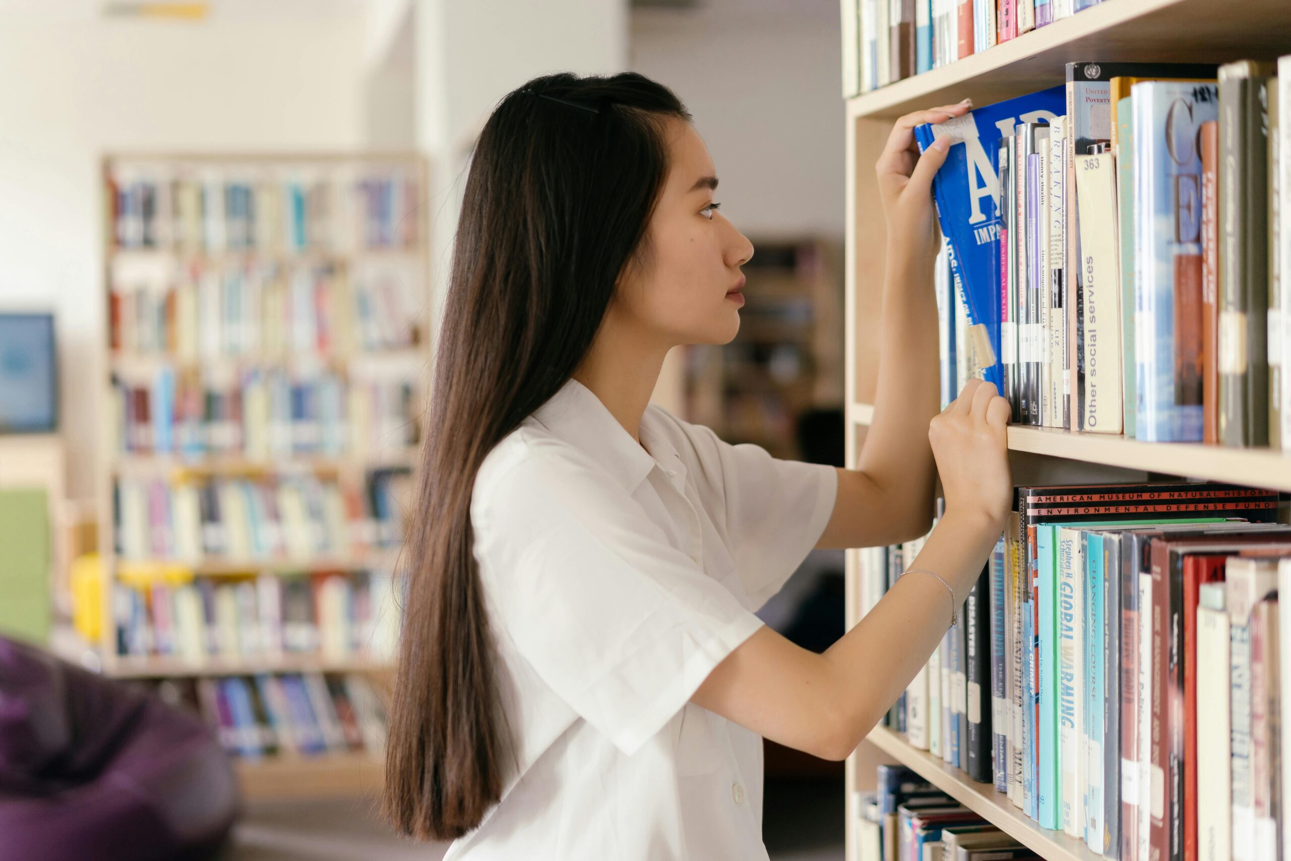 Student in library getting book from bookshelf