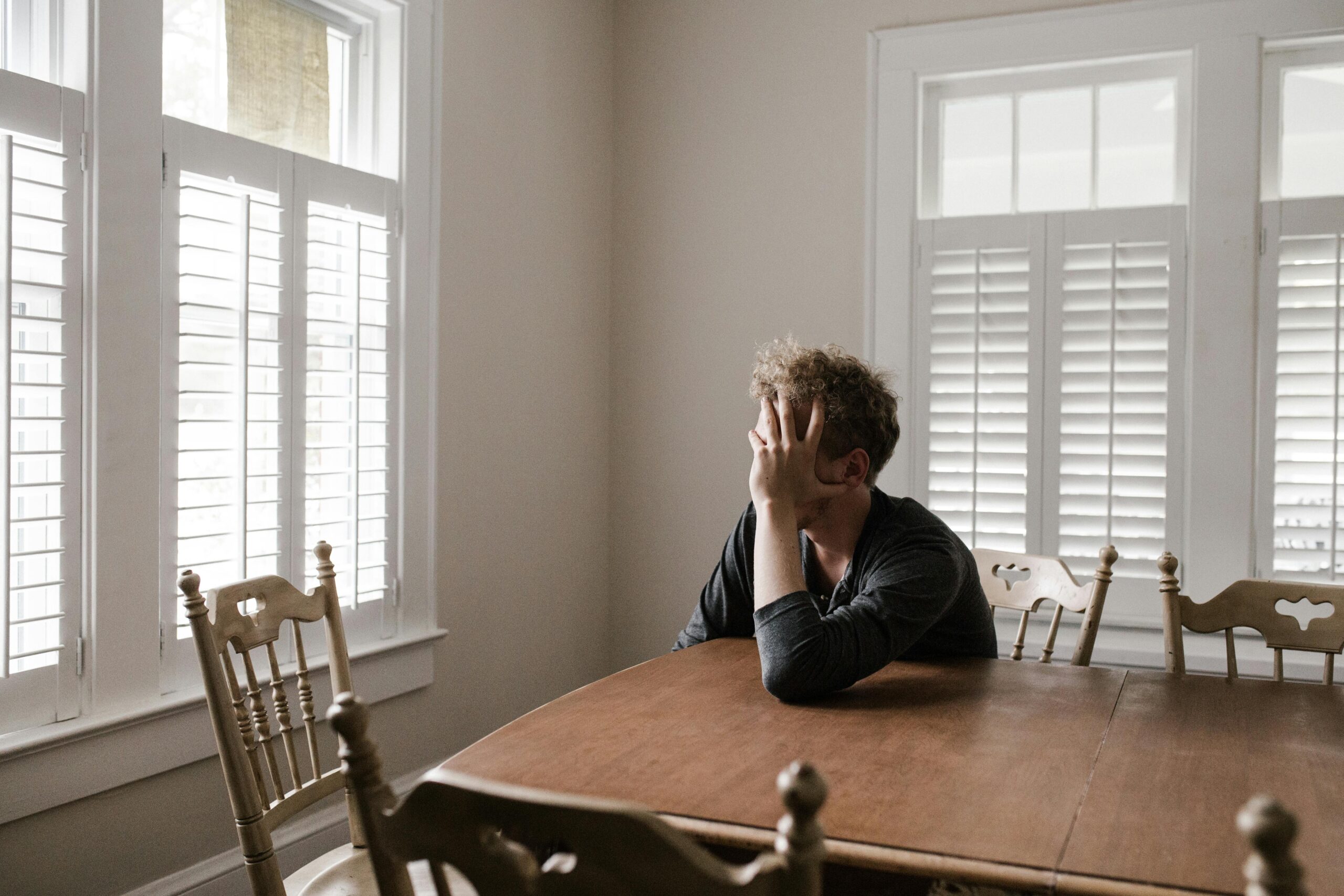 Sad young person sitting at table