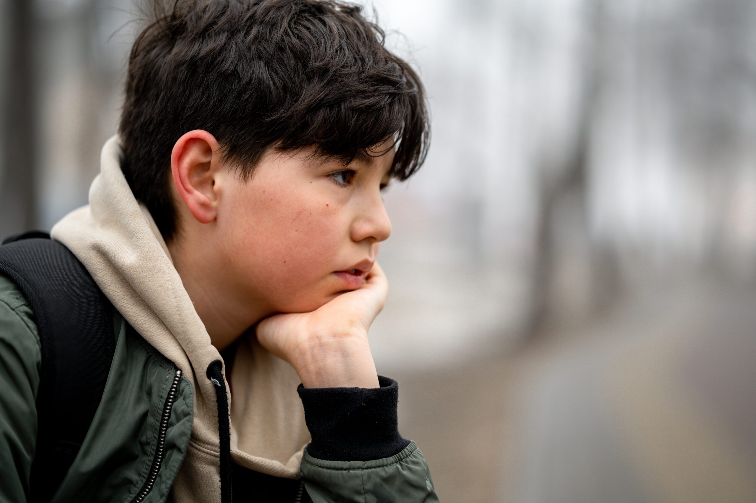 Teen sitting in park on a bench with a sad expression