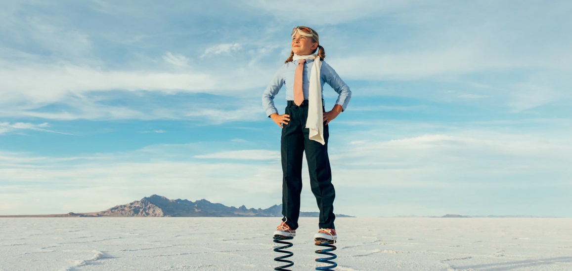 Child standing tall with mountains behind her as she smiles about new year resolutions